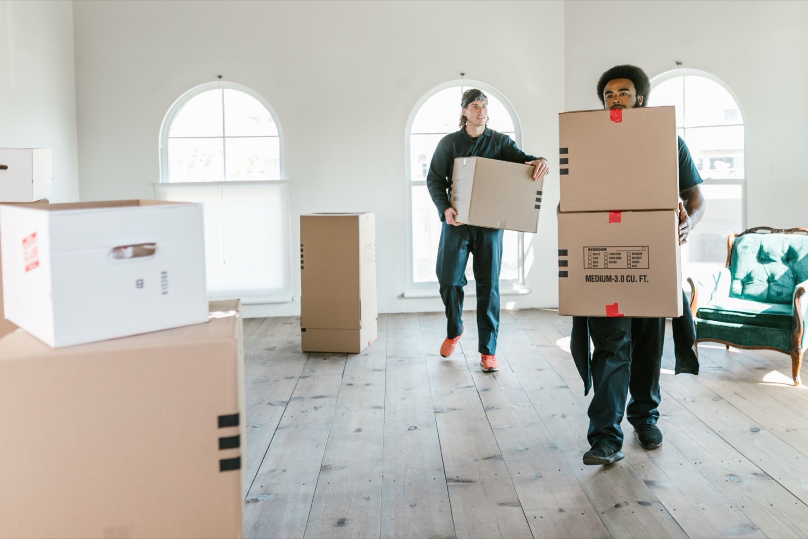 Two movers carrying boxes into a bright apartment — stock photo, replace with a real photo of your van/team