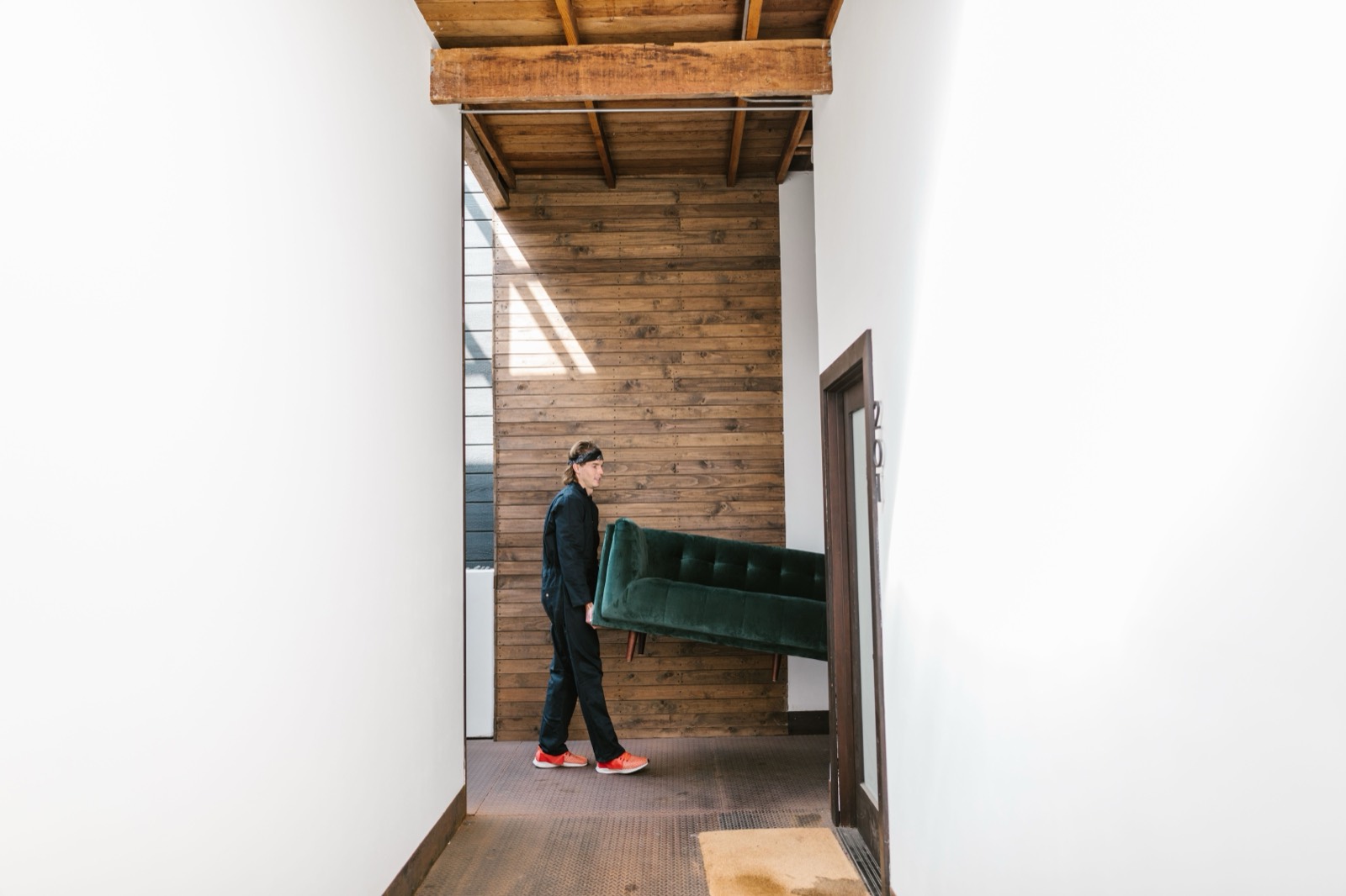 Mover carrying a sofa through a hallway — stock photo, replace with a real photo of your van/team
